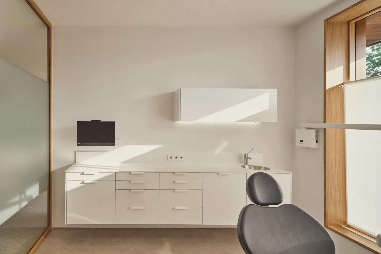 Gabinete dental con sillón, pantalla y armarios blancos