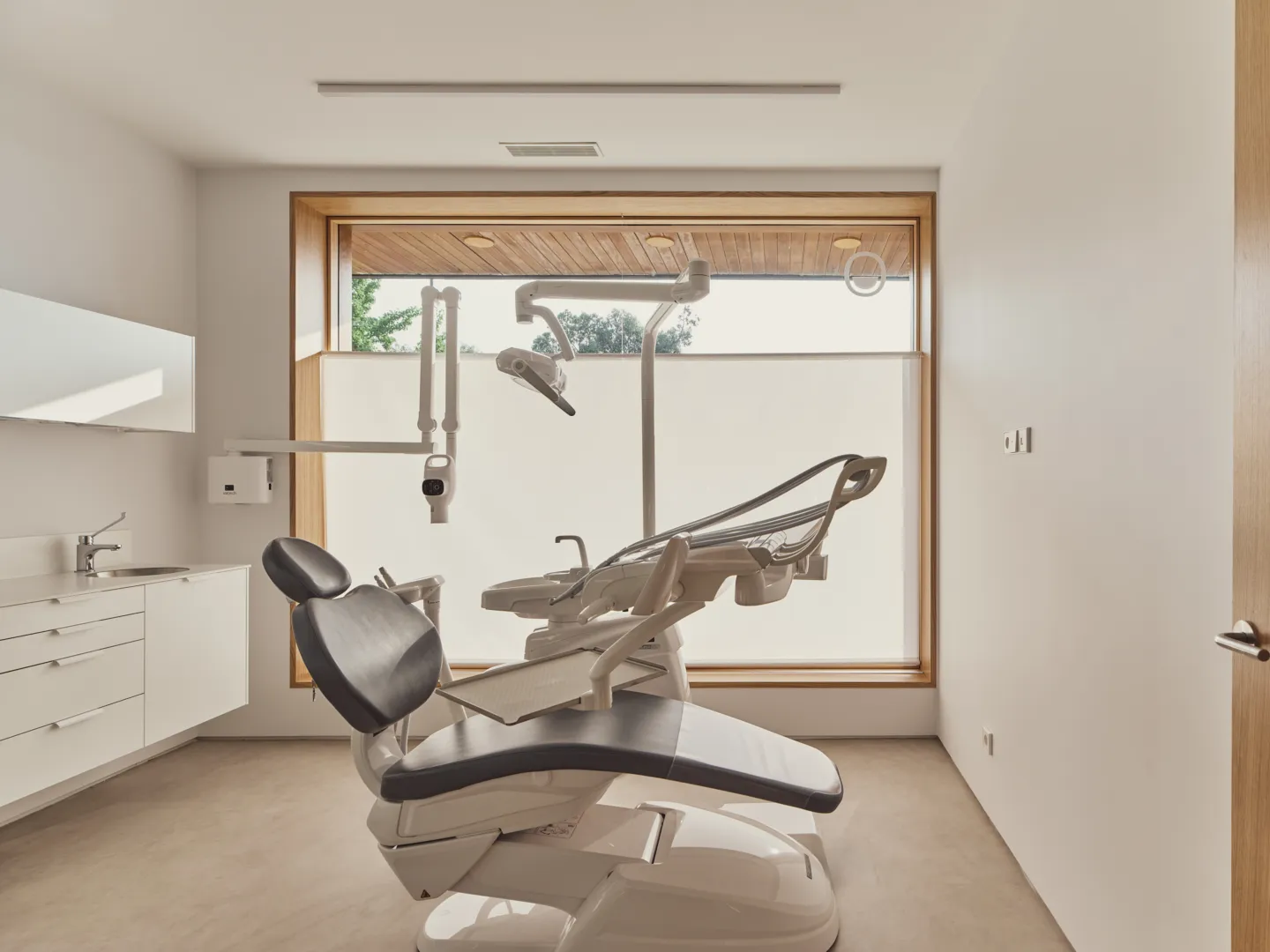 Gabinete dental luminoso con sillón y ventana enmarcada en madera